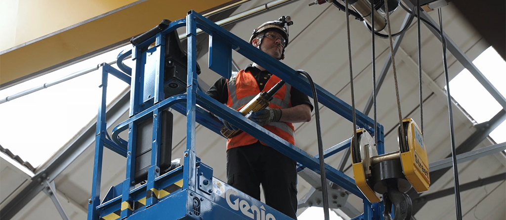 A man in a hard hat working on a crane hoist