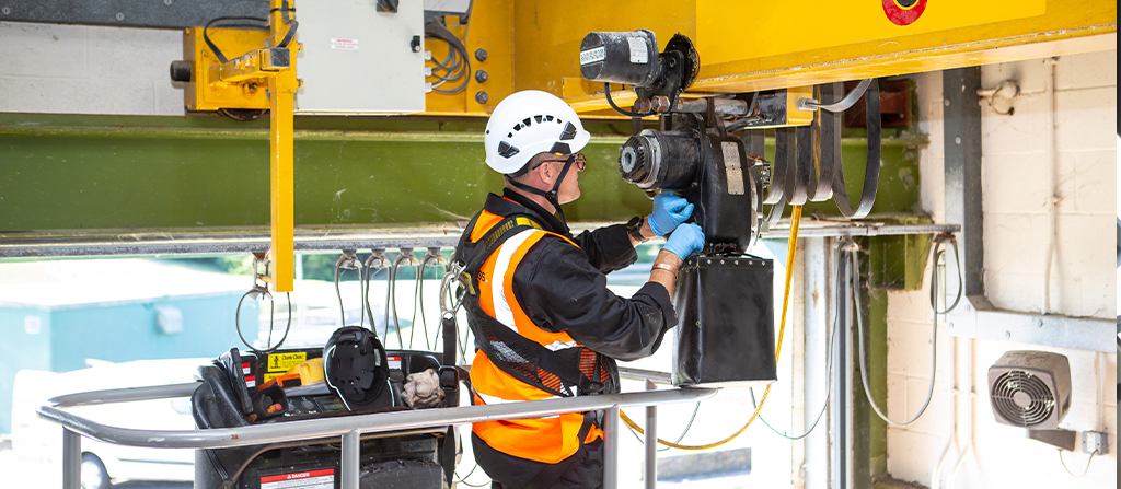A man in a hard hat working on a crane hoist