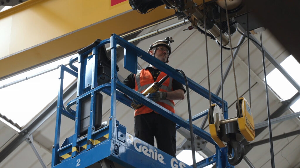 A person in a safety vest standing on a blue scissor lift