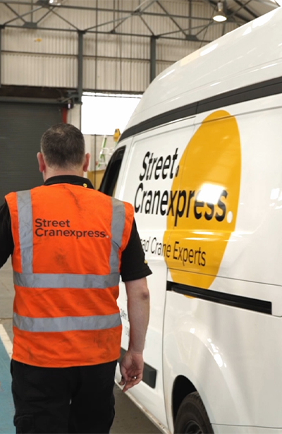 A man in a high vis walking next to a white van with black text that says Street Cranexpress