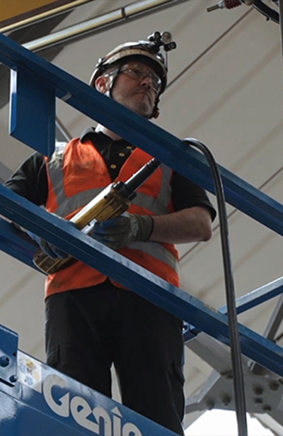 A person in a safety vest holding a crane pendant
