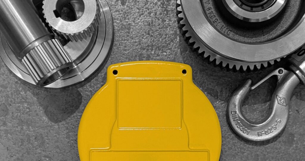 Assorted overhead crane spare parts placed on a painted concrete floor.